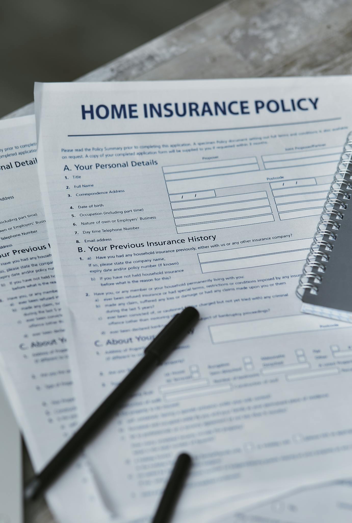 Flatlay image featuring a home insurance policy form and a notebook, shot from above.